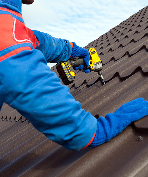 contractor with protection equipment and drill installing metal roofing at property beaverton or